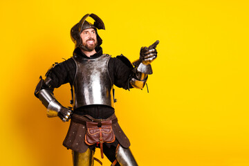 Young man in medieval knight's armor with yellow background expressing humor and charisma