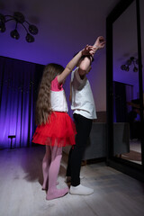 Children enjoying a playful dance in a vibrant room illuminated by purple lights during a cozy evening gathering