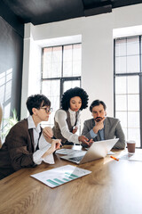 Business team analyzing financial data on laptop in modern office