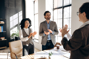 Business team applauding a colleague during a meeting in the office