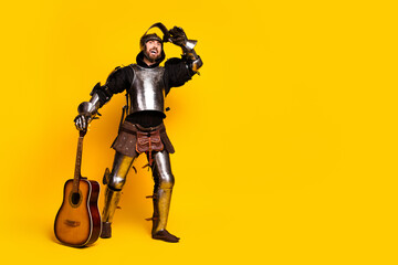 Armored man holding a guitar against a bright yellow backdrop displaying a medieval-modern fusion
