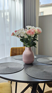Pink vase with flowers highlights refined dining space, flowers reflecting gentle pastel palette, flowers elevating modern interior vibe, appealing to brand imagery and editorial concepts