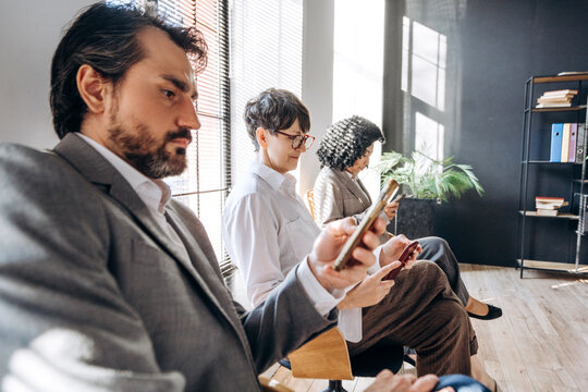 Business people using smartphones while waiting in office lobby