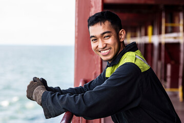 Portrait of a young Filipino marine engineer aboard a large container ship, gazing ahead with a thoughtful yet content expression—carrying both pride and longing across distant seas.