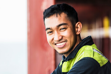 Portrait of a young Filipino marine engineer aboard a large container ship, gazing ahead with a...