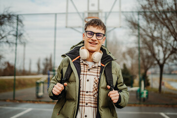 Fototapeta premium Portrait of a young man student smiling on a university basketball court 