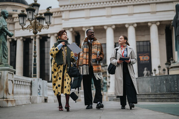 Three diverse individuals walking and conversing outdoors, carrying documents and devices,...