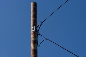 Close-up of a pole with optical cable fixed on it against blue sky.
