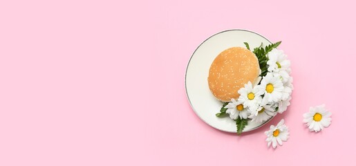 Burger with beautiful flowers on pink background with space for text, top view