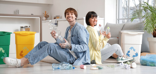 Young couple with garbage containers sorting rubbish in kitchen. Recycling concept