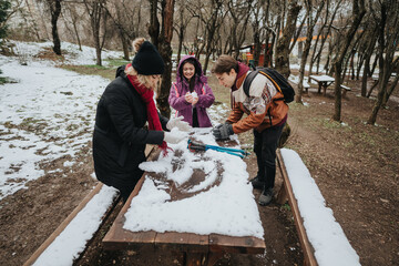 Three friends having fun in a snow-covered forest during winter, engaging in a creative and joyful...