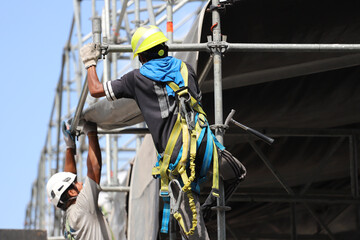 
Workers with harnesses and safety helmets working at height during stage assembly