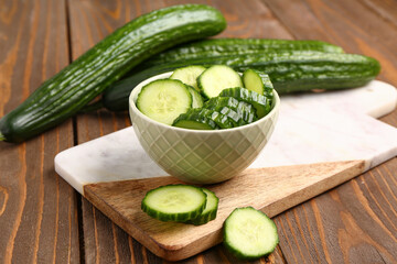 Bowl with fresh cut cucumber on wooden background