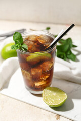 Glass of tasty Cuba Libre cocktail on light background