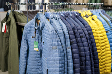 Colorful puffer jackets displayed in a retail store during autumn season for customers to browse