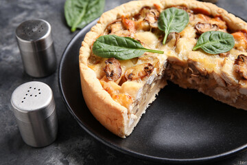 Mushroom pie with spinach leaves and cutlery on black grunge table