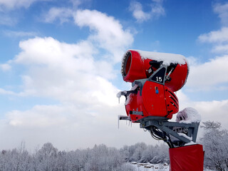 Snow cannon in a winter scenery on blue sky background