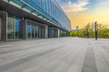 Empty brick floor and glass facade office building background at sunrise.