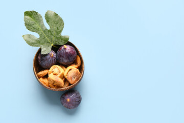 Bowl with sweet dried figs and fresh fruits on blue background