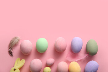 Painted Easter eggs with feathers on pink background