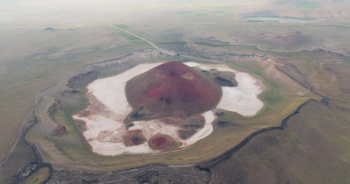 The drone dives to explore the conical structure at the center of the crater and the surrounding white, salt flats up close, showing the striking details and colors of the natural wonder.