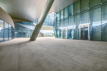Empty stone floor within modern architecture building featuring glass walls large pillar and open plaza background. © zhao dongfang
