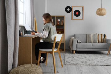 Female author with vintage typewriter at table in office