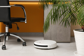 Modern robot vacuum cleaner near table at home