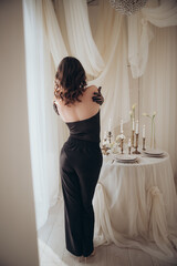 Romantic full-length portrait of a woman in black surrounded by vintage candles