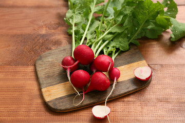 Board with fresh radishes on wooden background