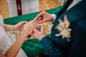 Close-up of groom placing a wedding ring on the bride’s finger during the ceremony, symbolizing love, unity, and commitment..