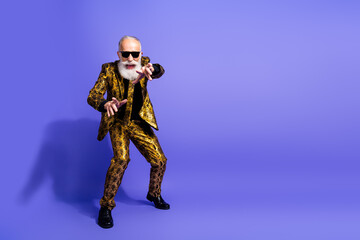 Stylish elderly man in a vibrant gold suit showing dynamic gestures against a vivid purple background