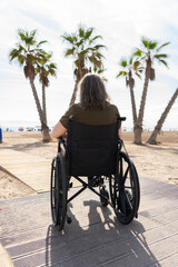 Senior woman enjoying beach accessibility on wheelchair ramp amidst palm trees