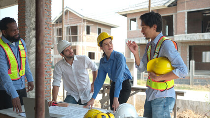 Group of architects and engineers work together to assess the residential home construction site's progress