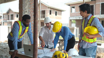 Group of architects and engineers work together to assess the residential home construction site's...