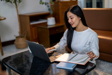 Naklejka premium A woman is sitting at a table with a laptop and a notebook