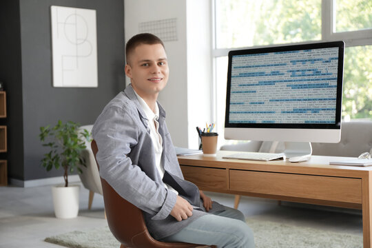 Young male programmer working with computer in modern home office