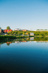 Obraz premium Tranquil countryside scene with colorful rooftops and heritage church under clear summer sky