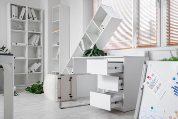 Interior of messy office with overturned furniture and houseplants after earthquake