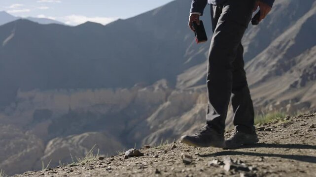 4K footage of Indian man walking along a mountain ridge in Ladakh, Lamayuru moonland of India, taking in the scenic view.