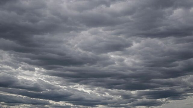 Dramatic sky with swirling gray clouds captured from a low-angle, creating a moody atmosphere, perfect for a time-lapse video. Live desktop wallpaper.