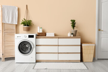 Interior of home laundry room with modern washing machine, dresser and basket