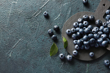 Cutting board with fresh ripe blueberry on dark blue grunge background