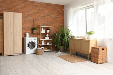 Interior of laundry room with washing machine, basket and shelf unit