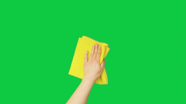 Green screen with a hand holding a yellow cleaning cloth, perfect for demonstration videos involving cleaning or presentation of objects.
