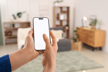Woman using blank mobile phone in living room, closeup