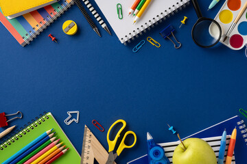 School supplies creatively arranged on a blue surface, including notebooks, pencils, scissors, and...