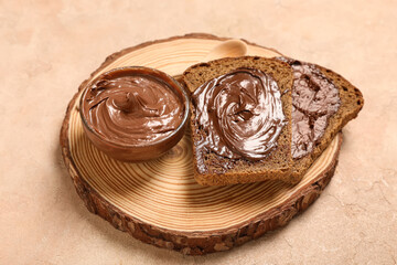 Wooden board of toasts with sweet chocolate spread on beige background
