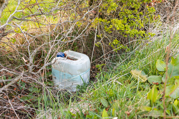 Environmental Waste Fly Tipping Concept: Discarded White Plastic Container Abandoned in Country...