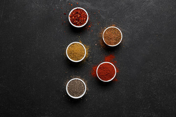 Composition with bowls of different spices on dark background